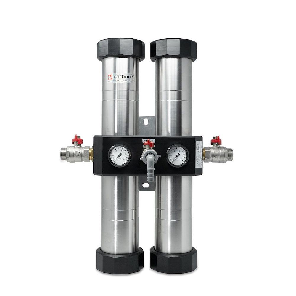 Der Carbonit QUADRO Hauswasserfilter von Carbonit besteht aus zwei Edelstahlzylindern, Manometern und Ventilen, die auf einer schwarzen Halterung montiert sind und eine effiziente Wasserfiltration für das ganze Haus ermöglichen.