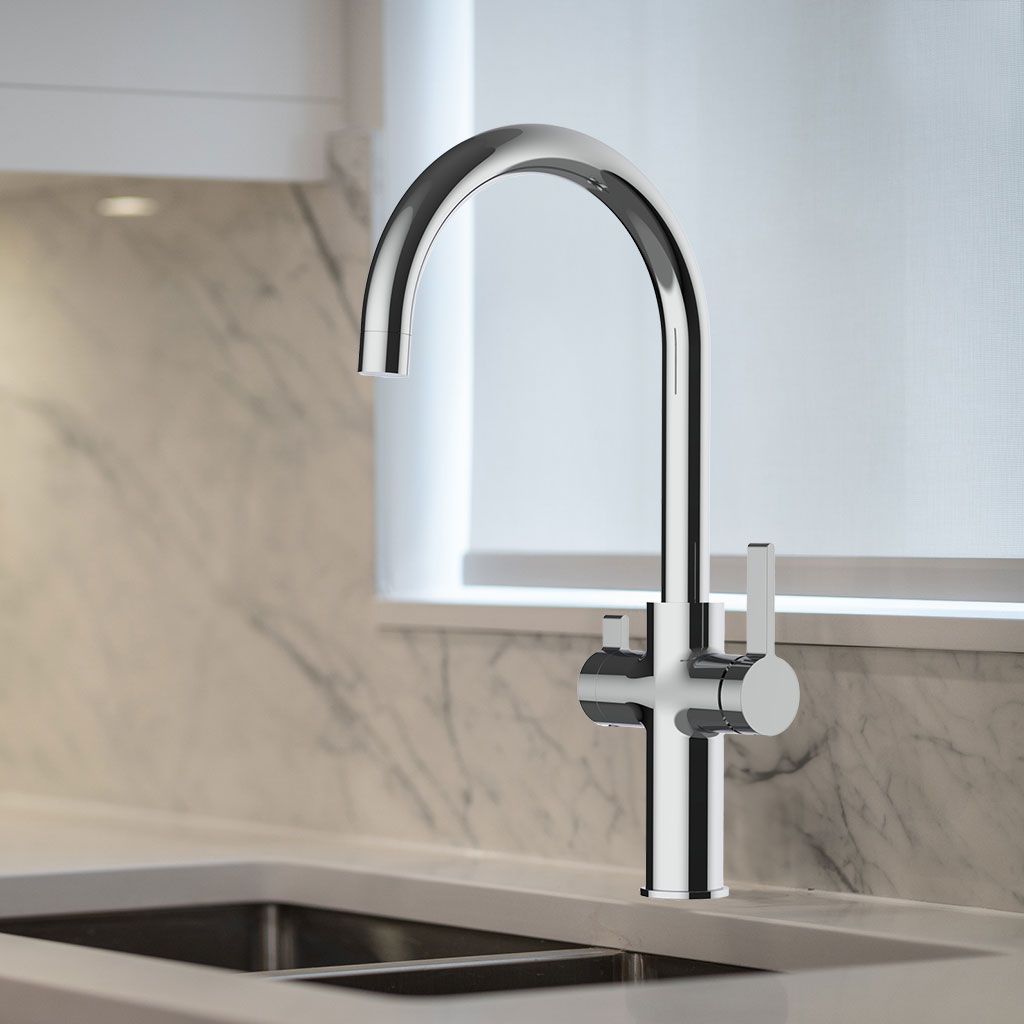 Die Furore NEO 3-Wege-Wasserhahn Chrom mit hohem, geschwungenem Auslauf und zwei Griffen ist über einem Waschbecken aus Edelstahl, vor einer Aufkantung aus hellem Marmor und unter einem Fenster mit weißer Blende montiert.