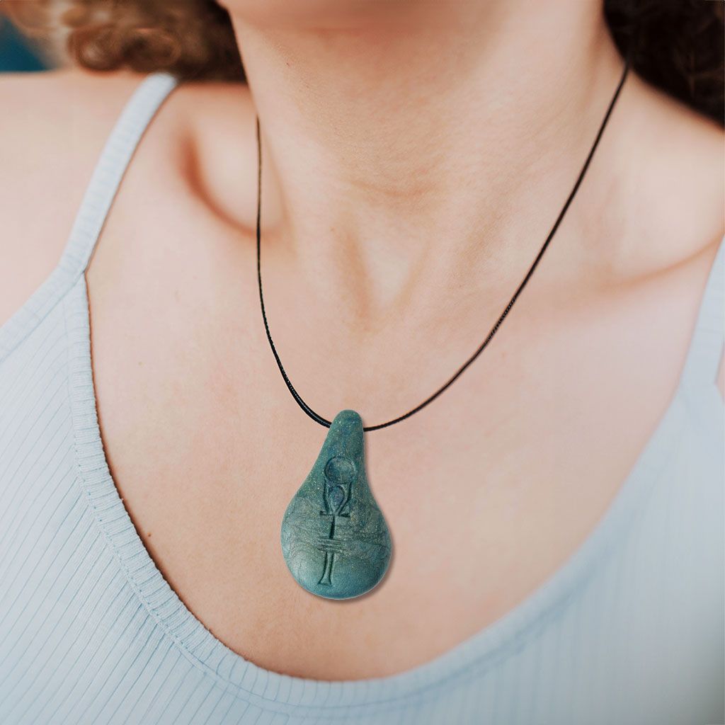 Eine Person trägt ein hellblaues, ärmelloses Oberteil und den Stein der Harmonie-Tropfenanhänger an einer schwarzen Kordel, der Energie und innere Balance symbolisiert.