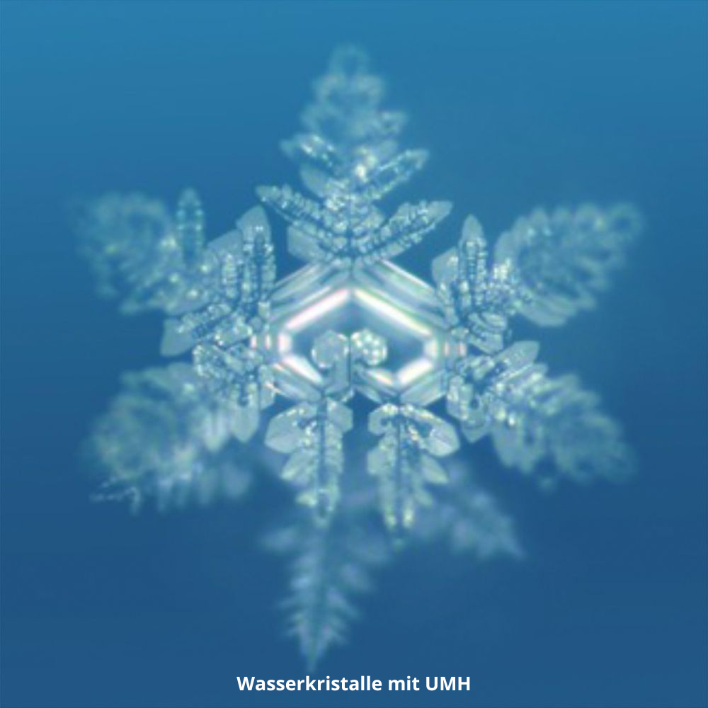 Ein detaillierter, symmetrischer Schneeflocken-Kristall ist vor einem blauen Hintergrund abgebildet. Der weiße Text am unteren Rand lautet: Wasserkristalle mit UMH PURE GOLD von UMH für beste Trinkwasserqualität.