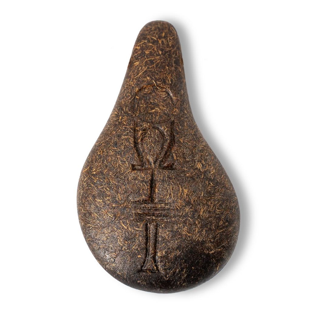Ein tropfenförmiger, brauner Stein der Harmonie aus organischem Holzgemisch mit einer leicht faserigen Struktur und einem eingravierten Ankh-Omega-Symbol ruht auf einem schlichten weißen Hintergrund.