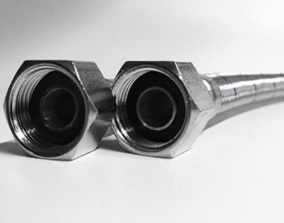 Nahaufnahme von zwei geflochtenen Metallschläuchen mit Sechskantgewinde, die nebeneinander auf einer weißen Fläche liegen.